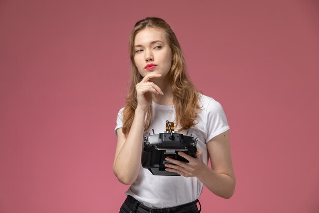 Vista frontal jovem mulher atraente em camiseta branca posando com expressão pensativa na parede rosa modelo cor feminino jovem