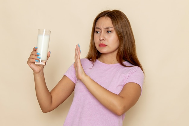 Vista frontal, jovem mulher atraente em camiseta rosa e jeans azul segurando um copo de leite