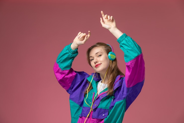 Foto grátis vista frontal jovem mulher atraente em t-shirt branca casaco colorido dançando na parede rosa cor modelo feminino jovem