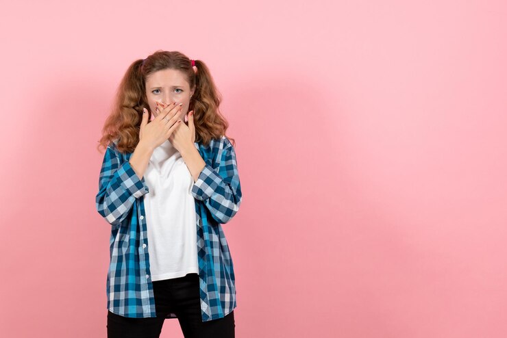 Foto grátis vista frontal jovem mulher com camisa quadriculada azul cobrindo a boca na parede rosa mulher criança jovem modelo cor emoção