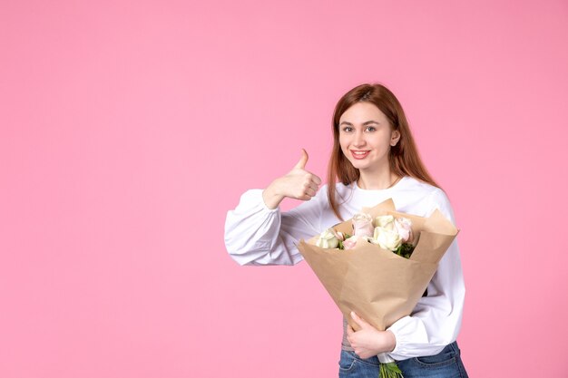 Vista frontal jovem mulher com flores como dia da mulher presente em fundo rosa horizontal feminino março mulher sensual igualdade rosa amor