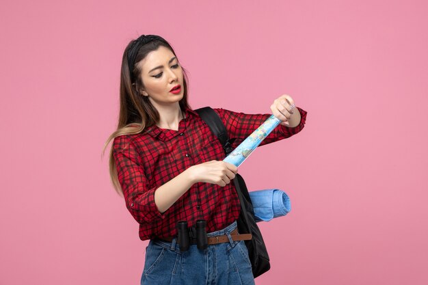 Vista frontal jovem mulher de camisa vermelha com mapa na cor de fundo rosa moda mulher