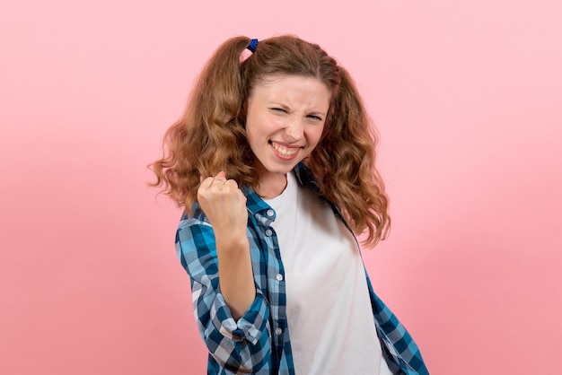 Vista frontal jovem mulher em camisa quadriculada regozijando-se no fundo rosa jovem mulher cor emoções modelo garoto