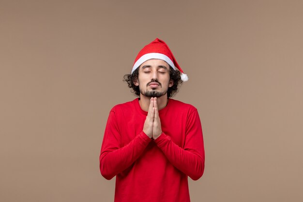 Vista frontal jovem orando em emoções de fundo marrom nas férias de Natal