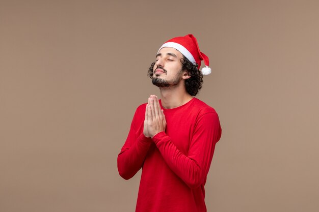 Vista frontal jovem orando em fundo marrom, férias de emoções de natal