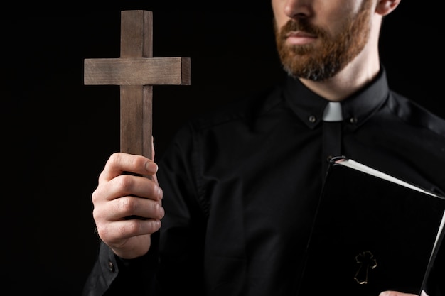 Vista frontal jovem padre segurando cruz