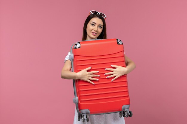 Vista frontal jovem se preparando para as férias segurando sua bolsa em fundo rosa viagem viagem feminina viagem mar no exterior