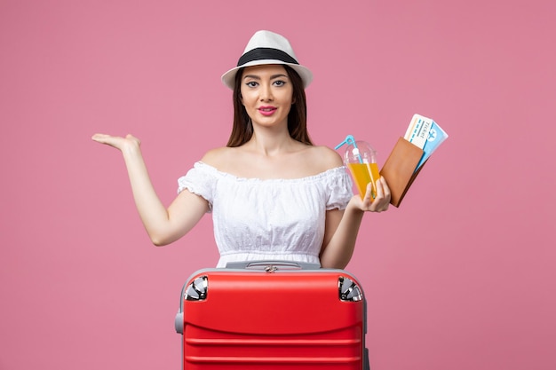 Vista frontal jovem segurando bilhetes de férias e posando na parede rosa verão viagem emoção avião viagem