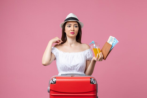 Vista frontal jovem segurando bilhetes de férias e posando na parede rosa verão viagem emoção avião viagem