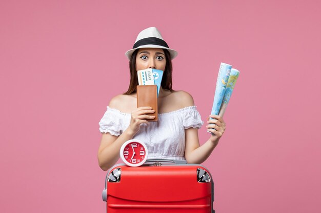 Vista frontal jovem segurando bilhetes e mapa de férias na parede rosa calor férias viagem verão mulher viagem