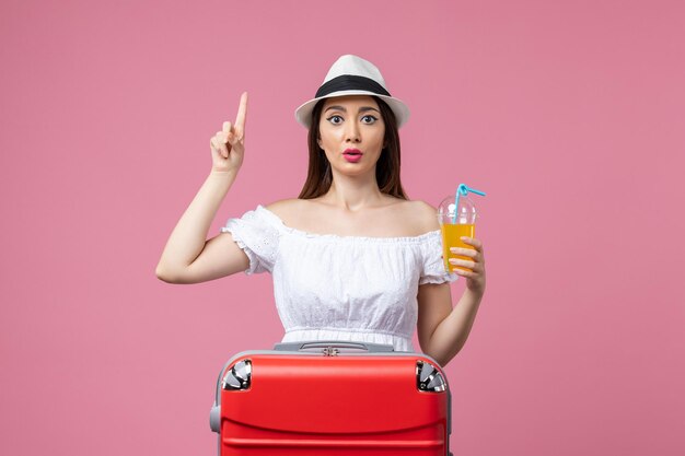 Vista frontal jovem segurando coquetel nas férias de verão na parede rosa emoção férias avião viagem verão viagem