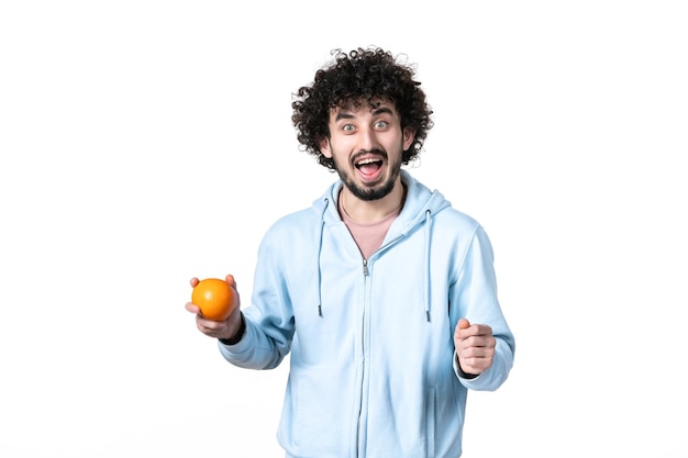 Vista frontal jovem segurando laranja fresca no fundo branco músculo da saúde perdendo peso humano emagrecimento medição do corpo da fruta