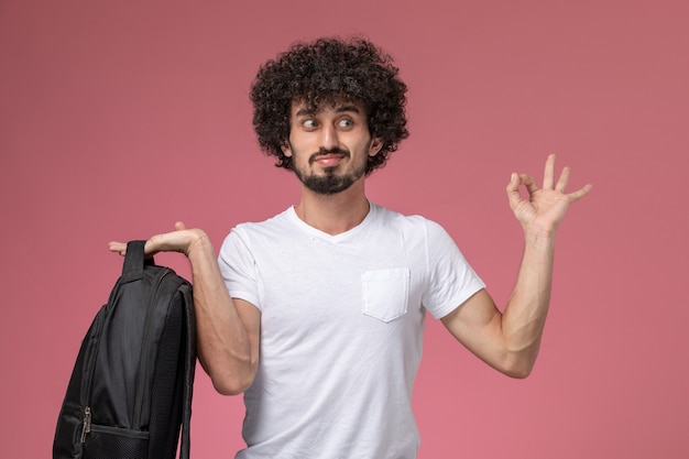 Vista frontal jovem segurando sua mochila e fazendo gesto de ok