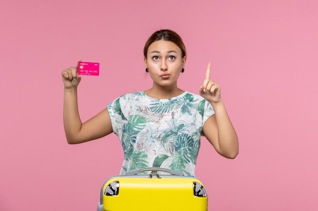 Vista frontal jovem segurando um cartão do banco de férias na parede rosa verão descanso cores viagem férias mulher