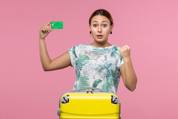 Vista frontal jovem segurando um cartão do banco de férias na parede rosa verão viagem viagem descanso mulher férias