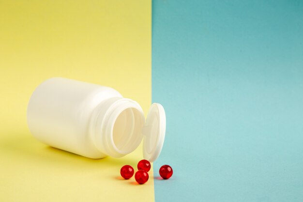 vista frontal lata de plástico branco com comprimidos vermelhos em fundo amarelo-azul