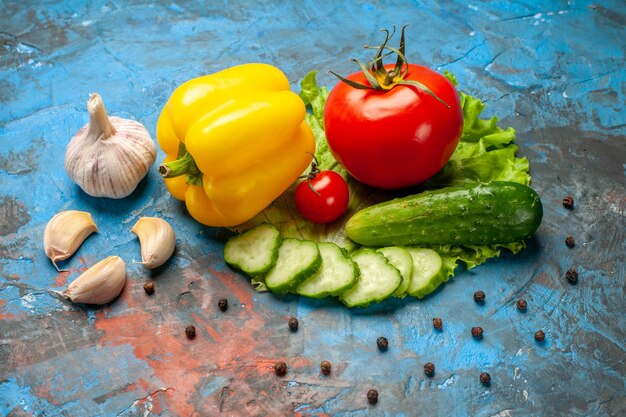 Vista frontal legumes frescos pepino tomate salada verde e alho no fundo azul refeição salada saúde alimentos maduros cor