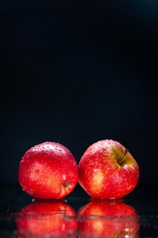 Vista frontal maçã vermelha fresca sobre fundo preto cor madura árvore madura escuridão foto pera exótica saborosa