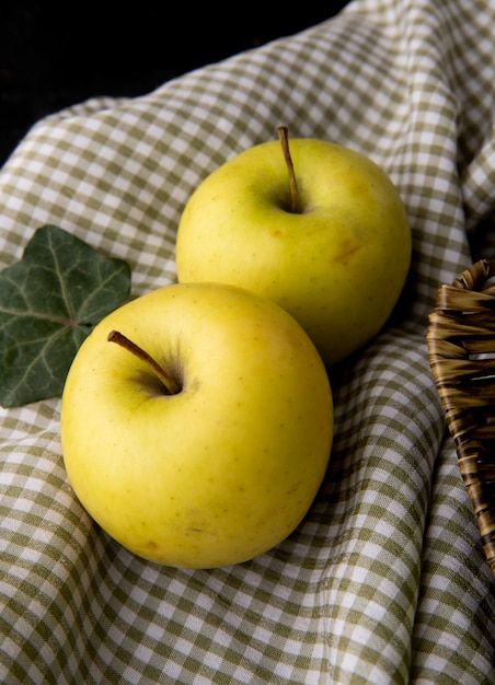 Vista frontal maçãs amarelas numa toalha de mesa quadriculada em uma mesa