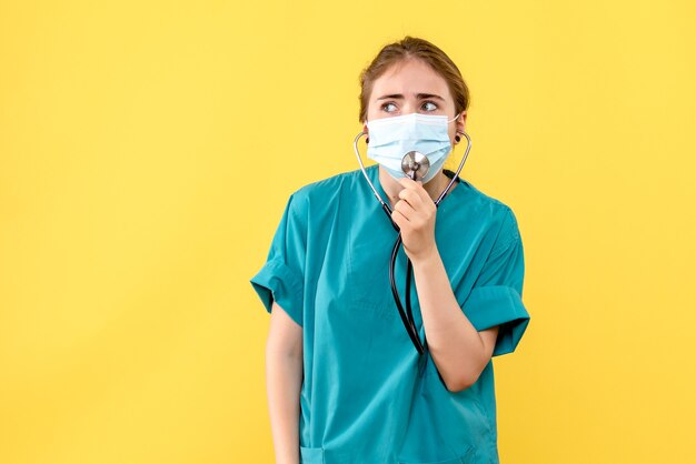 Vista frontal médica com máscara na mesa amarela, vírus da saúde, pandemia covid