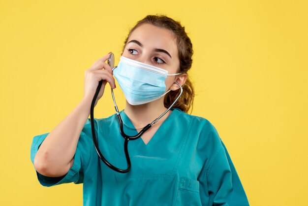 Vista frontal médica em camisa médica e máscara com estetoscópio, vírus, cor uniforme, emoção, saúde