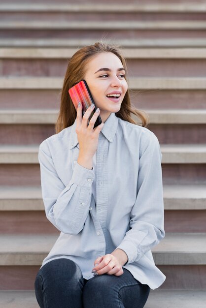 Vista frontal menina loira falando no telefone