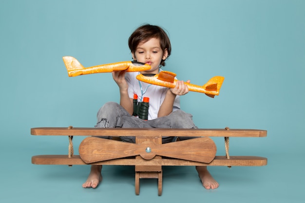 Foto grátis vista frontal menino brincando com aviões de brinquedo no chão azul