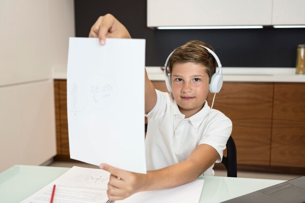 Vista frontal, menino jovem, segurando papel, em casa