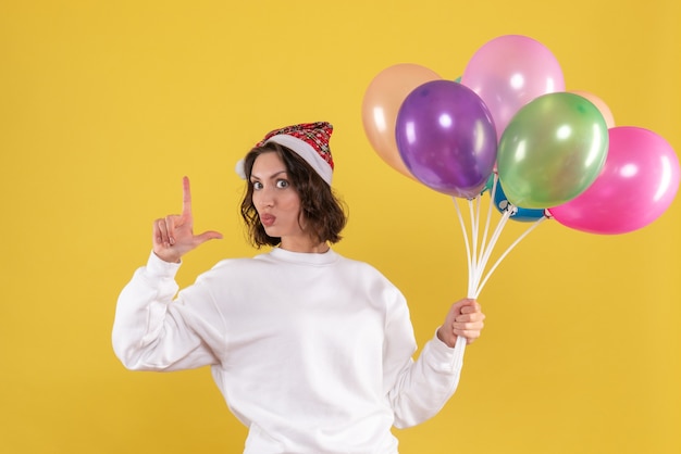 Vista frontal muito feminina segurando balões coloridos em amarelo