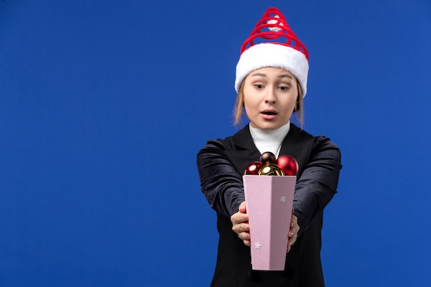 Foto grátis vista frontal muito feminina segurando brinquedos da árvore de natal na parede azul feriado de ano novo