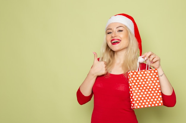 Vista frontal muito feminina segurando presente em um pequeno pacote na parede verde férias natal neve cor ano novo emoções