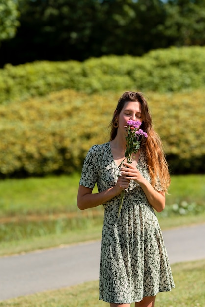 Foto grátis vista frontal mulher cheirando flores