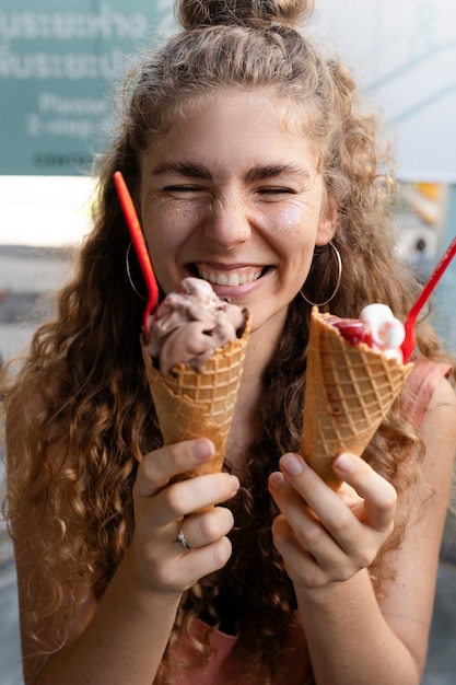 Vista frontal mulher feliz segurando casquinhas de sorvete