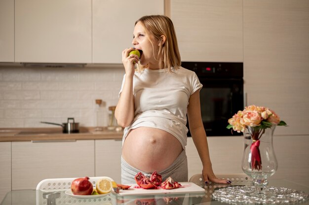 Vista frontal mulher grávida comendo uma maçã
