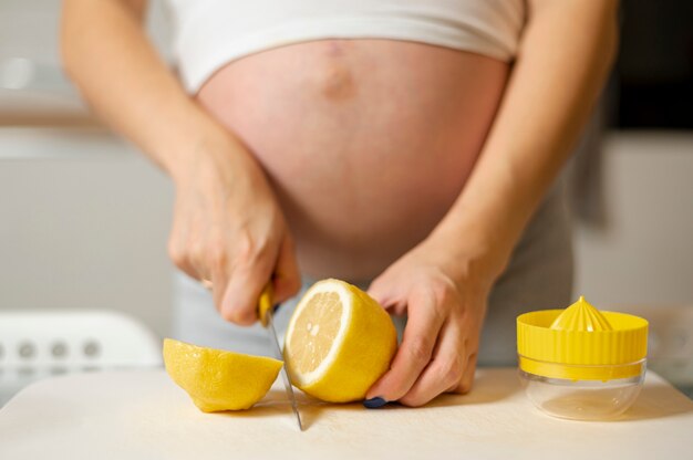 Vista frontal mulher grávida mãos cortar um limão