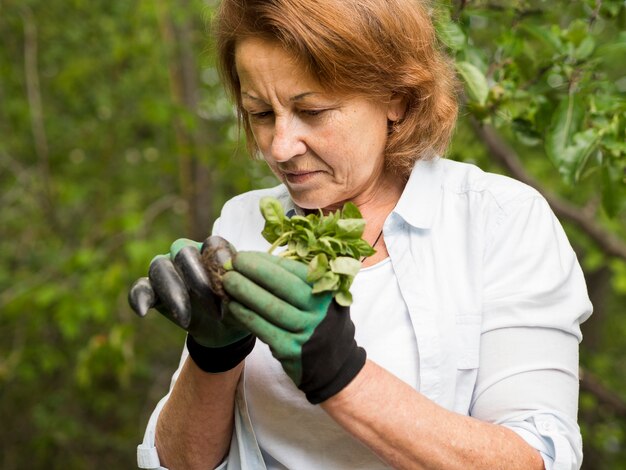Vista frontal mulher segurando uma pequena planta nas mãos