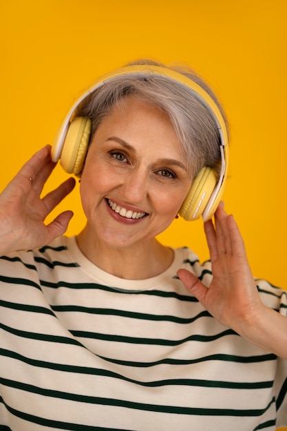Vista frontal mulher sênior posando com fones de ouvido