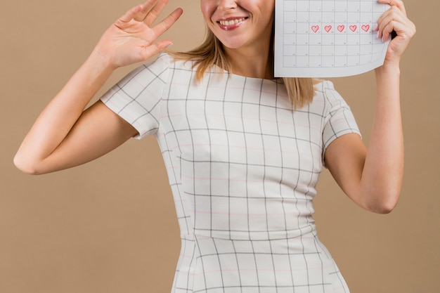 Vista frontal mulher sorrindo e segurando a mesa de menstruação