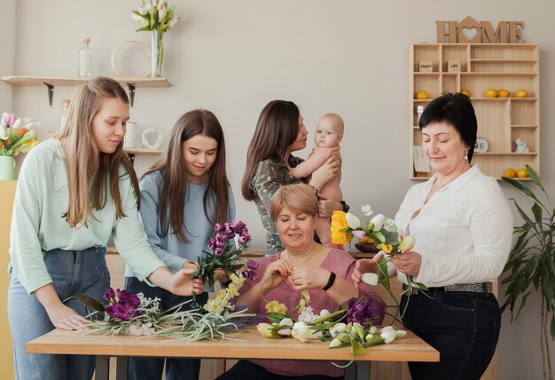 Vista frontal mulheres e bebê em pé ao redor de uma mesa