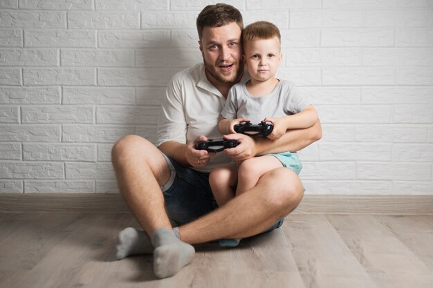 Vista frontal pai e filho jogando videogame