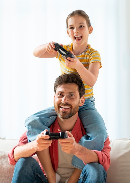 Vista frontal pai e menina jogando videogame