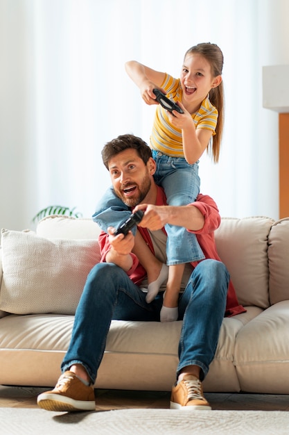 Vista frontal pai e menina jogando videogame