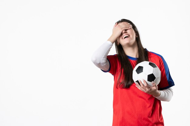 Vista frontal rindo jovem mulher em roupas esportivas com bola de futebol