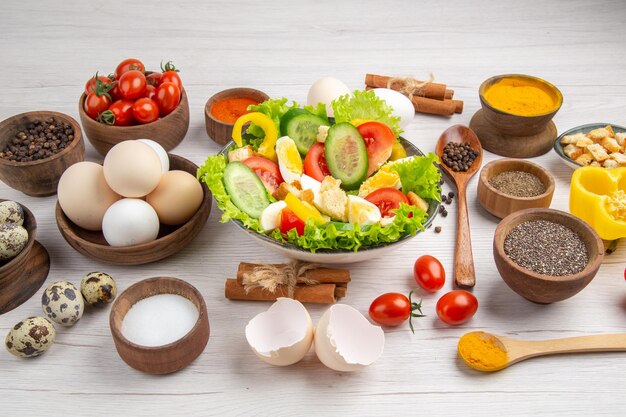 Vista frontal saborosa salada de legumes com temperos de ovos e tomates em fundo branco cor de comida salada madura café da manhã almoço refeição