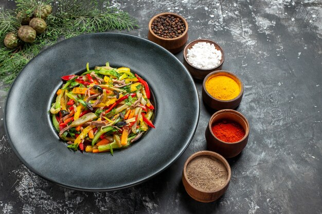 Vista frontal saborosa salada de vegetais com temperos na mesa cinza