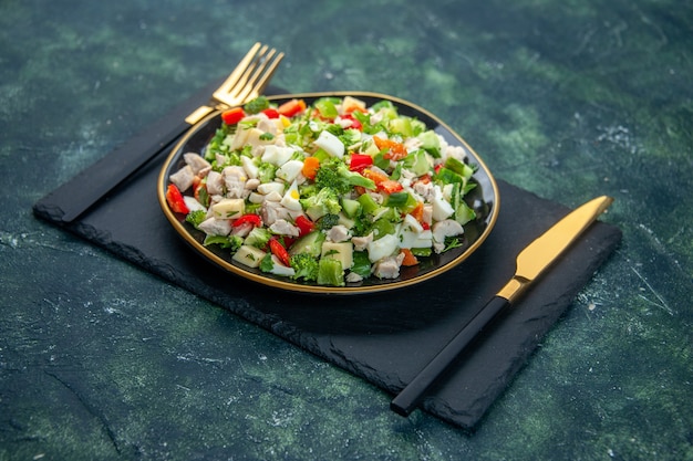 vista frontal saborosa salada de vegetais dentro do prato com garfo em fundo escuro