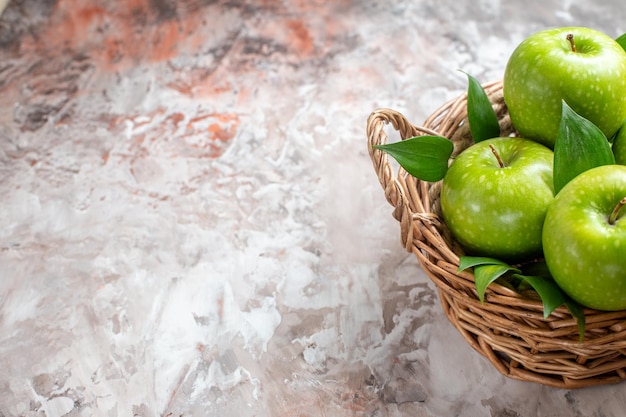 Vista frontal saborosas maçãs verdes dentro da cesta em fundo claro