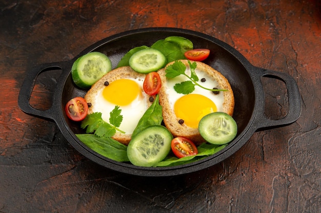 Vista frontal saborosas torradas de ovos com legumes fatiados em um fundo escuro refeição ovo café da manhã almoço fritar foto colorida torradeira