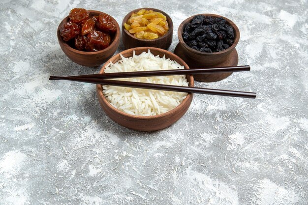 Vista frontal saboroso arroz cozido dentro de um prato marrom com passas na mesa branca