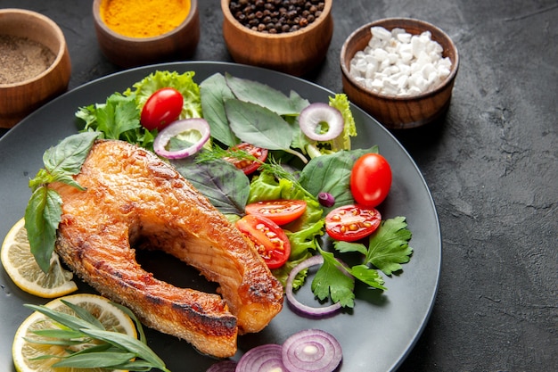 Vista frontal saboroso peixe cozido com legumes frescos e temperos na cor de fundo escuro comida carne marisco prato foto